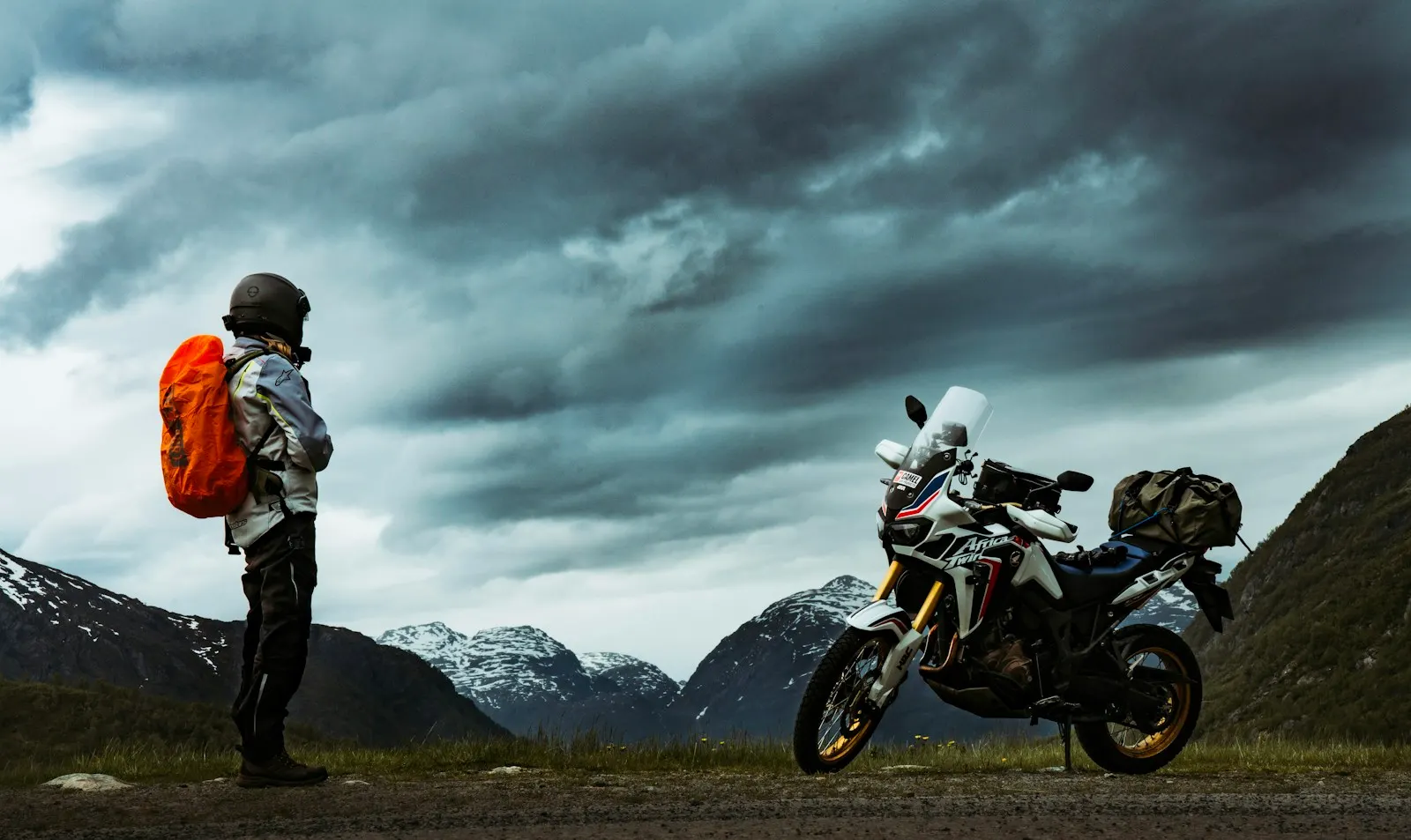 Motard et sa moto de voyage face à la montagne