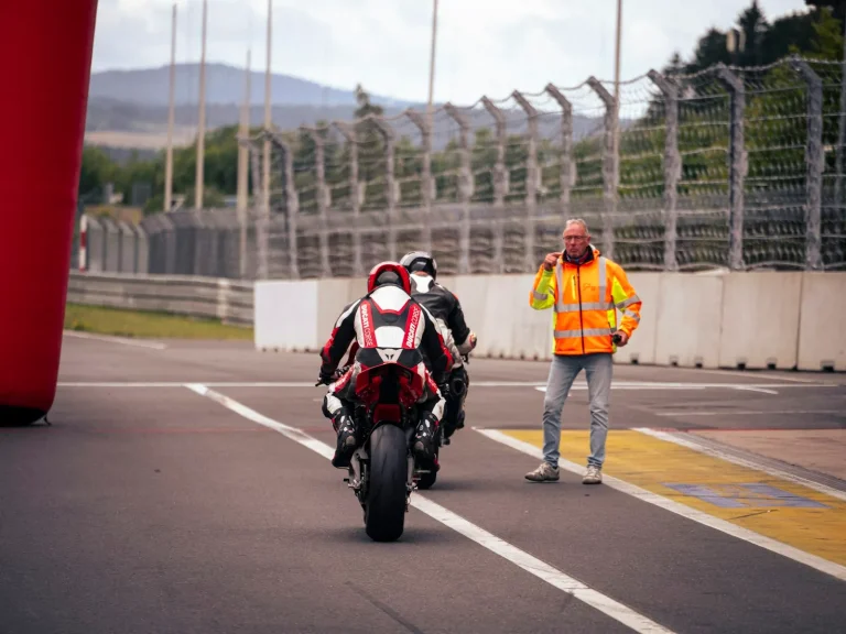 Motards en roulage sur une piste, guidés par un commissaire