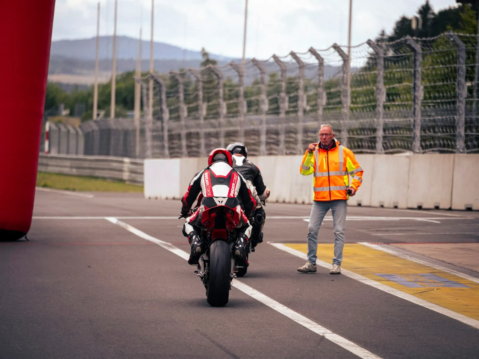 Motards en roulage sur une piste, guidés par un commissaire